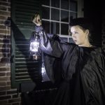 A guide from the Haunted Walk holding up a lantern that is lit up